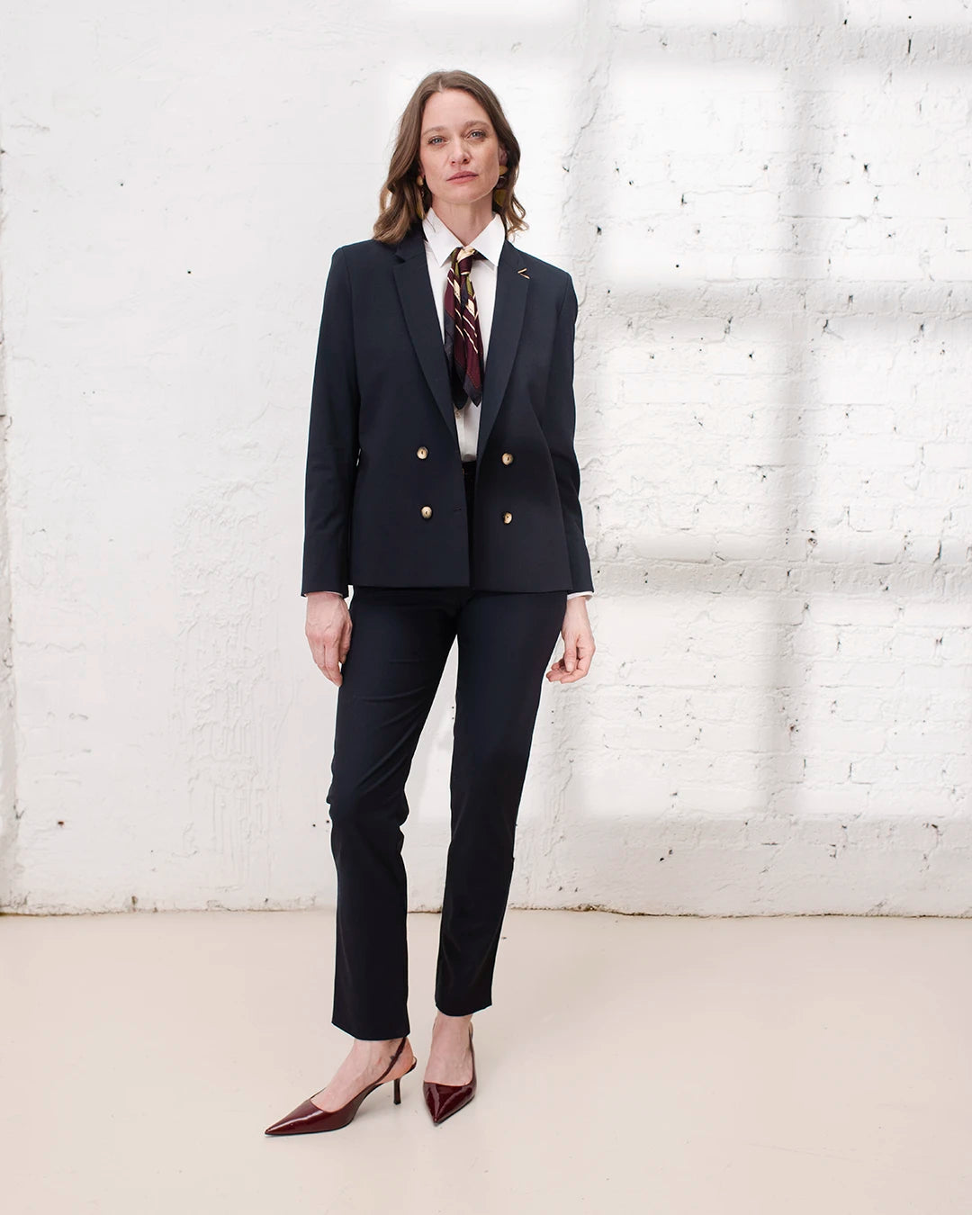 Veste croisée bleu marine femme portée avec pantalon cigarette pour un look de travail sophistiqué.