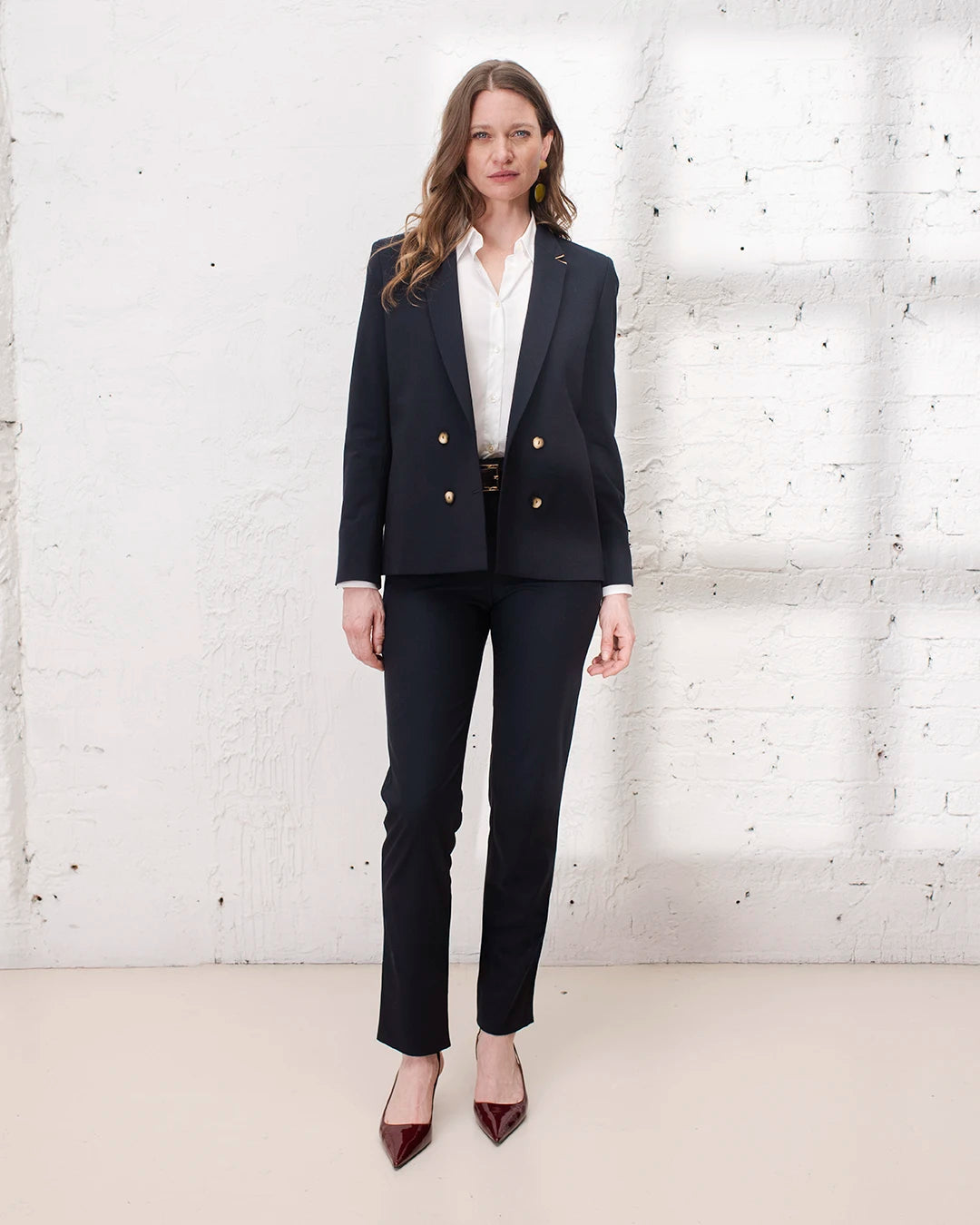 Look professionnel femme avec veste croisée bleu marine et pantalon cigarette assorti.