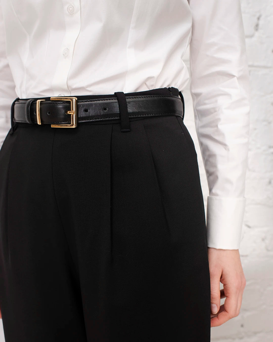 Tenue business chic femme avec chemise blanche cintrée, boutons de manchette et pantalon tailleur noir.