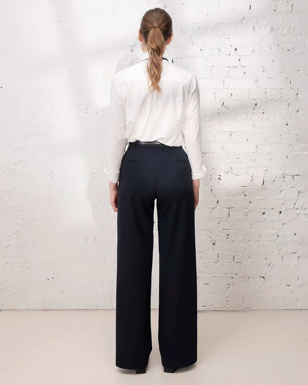 Veste de tailleur bleu marine cintrée avec pantalon large pour une tenue de travail élégante.