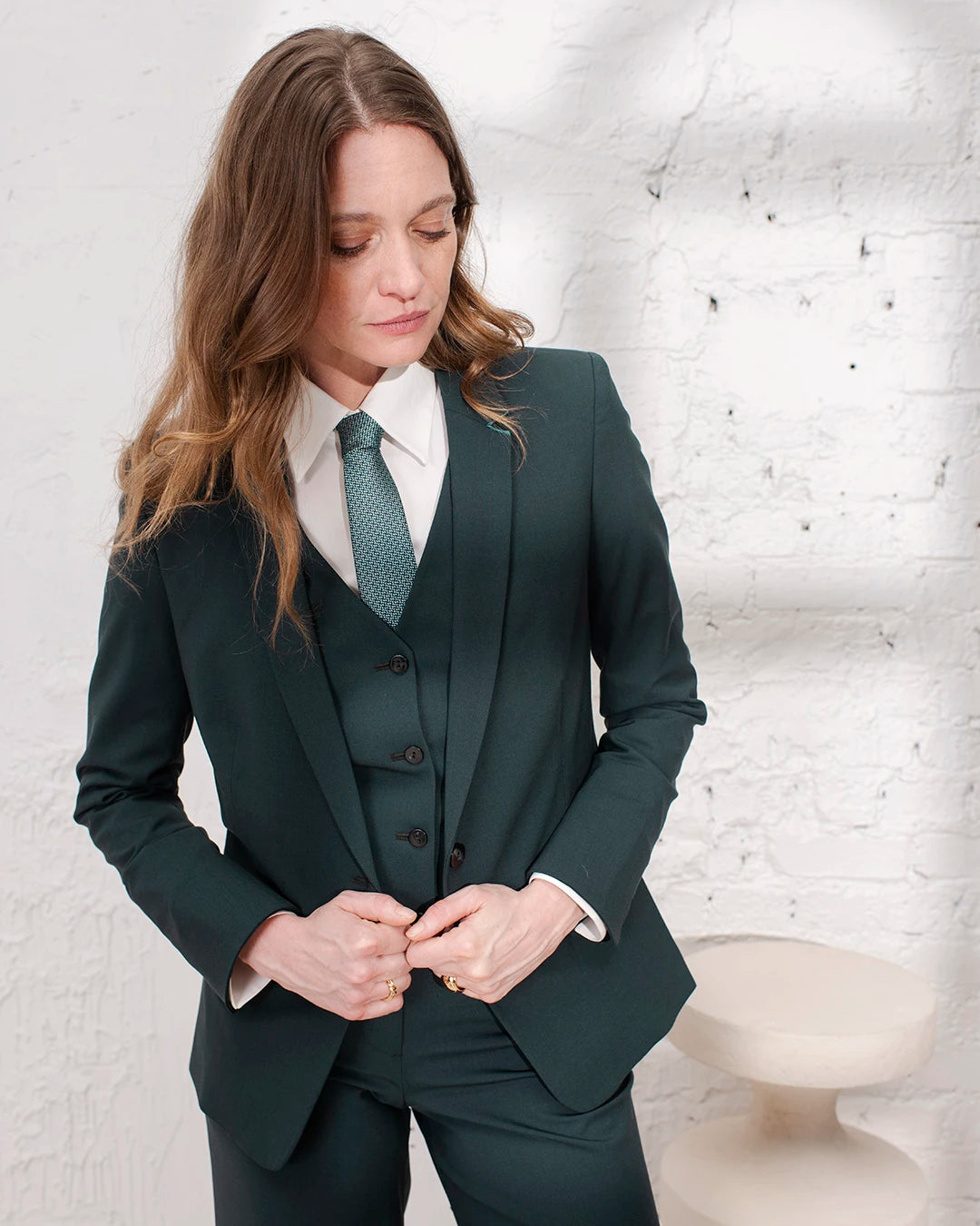 Tenue chic femme avec tailleur vert bouteille, veste cintrée, gilet et pantalon large assorti.