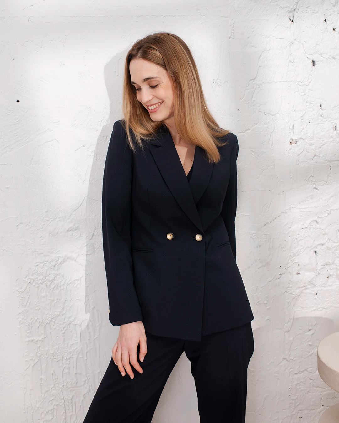 Tailleur femme bleu marine trois pièces avec veste croisée ceinturée cintrée, gilet sans manches et pantalon droit.