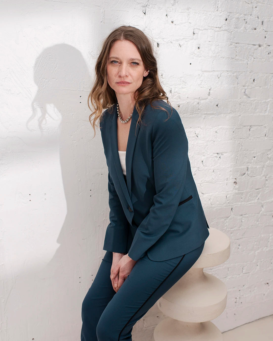 Tenue de bureau femme avec tailleur bleu gris, veste cintrée et pantalon cigarette chic.