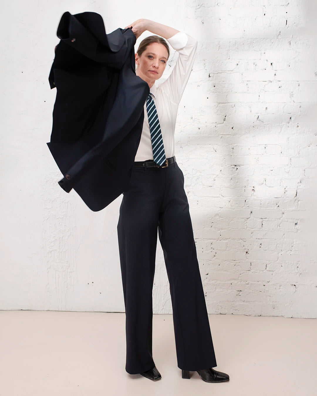 Look professionnel femme avec veste cintrée bleu marine et pantalon large assorti, style tailoring.