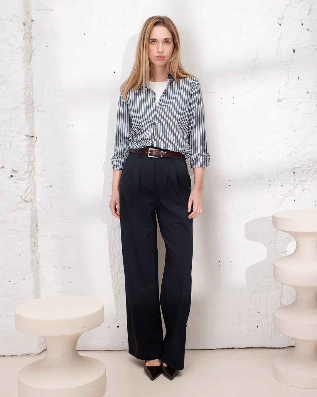 Pantalon tailleur palazzo bleu marine porté avec veste courte pour un look bureau chic.