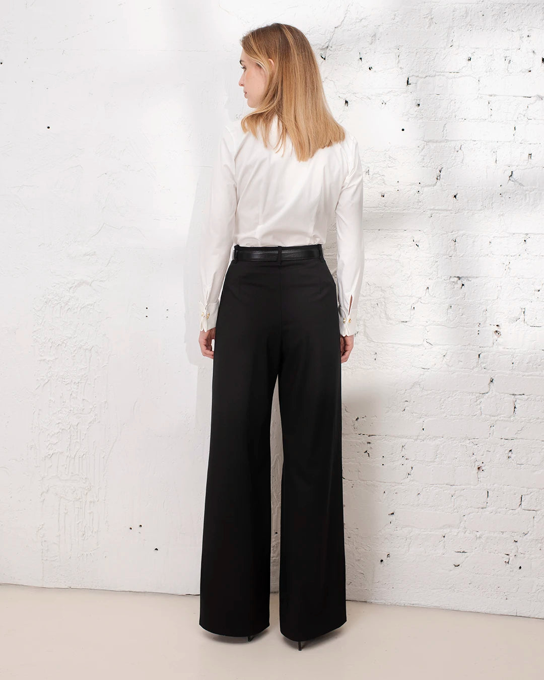 Tenue professionnelle femme avec pantalon noir large et chemise blanche structurée