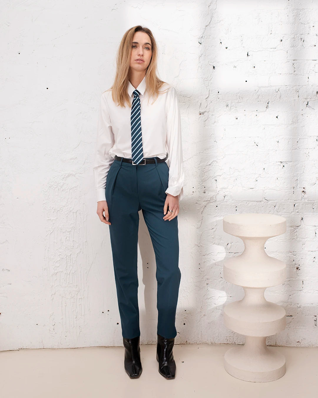 Tailleur femme bleu gris avec veste croisée et pantalon carotte pour un style bureau chic.