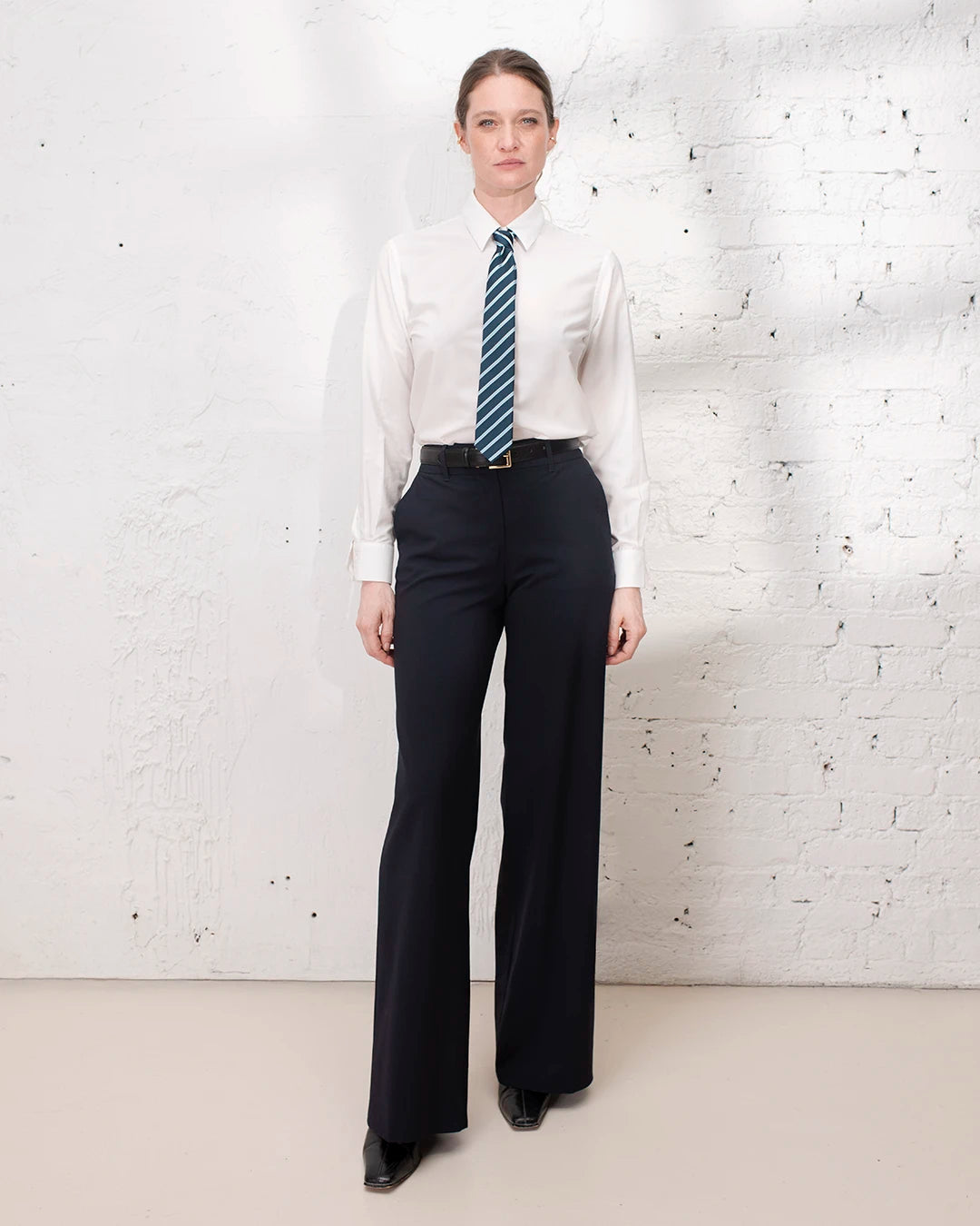 Tailleur femme bleu marine avec veste cintrée et pantalon large pour une tenue de travail chic.