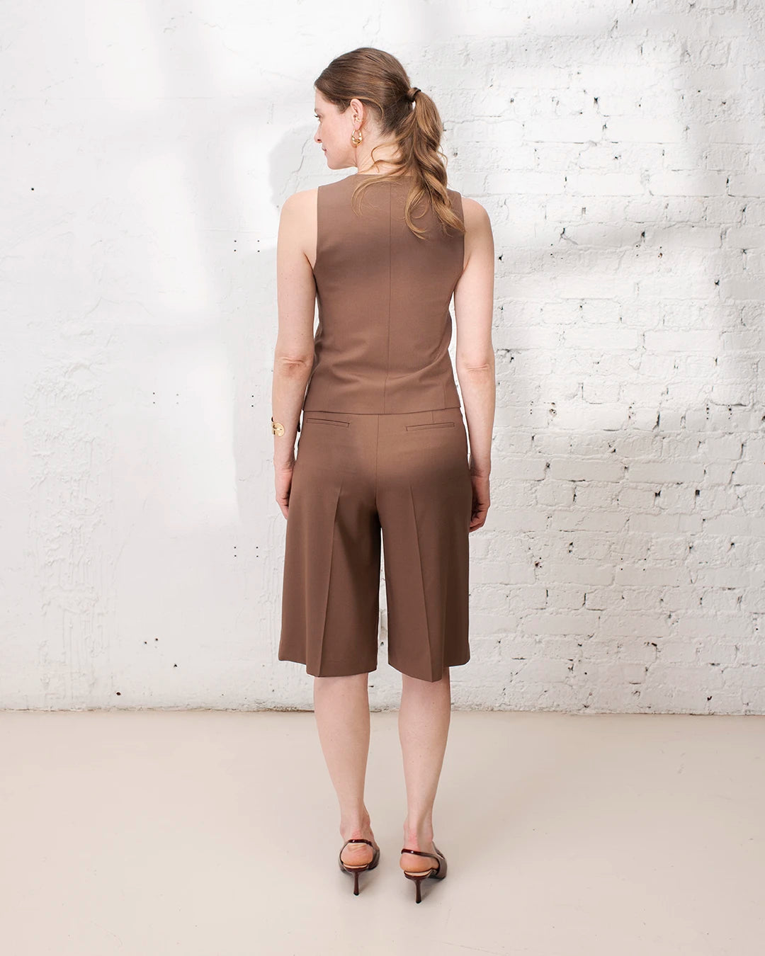 Outfit élégant femme avec bermuda de tailleur marron, gilet sans manches et veste structurée.