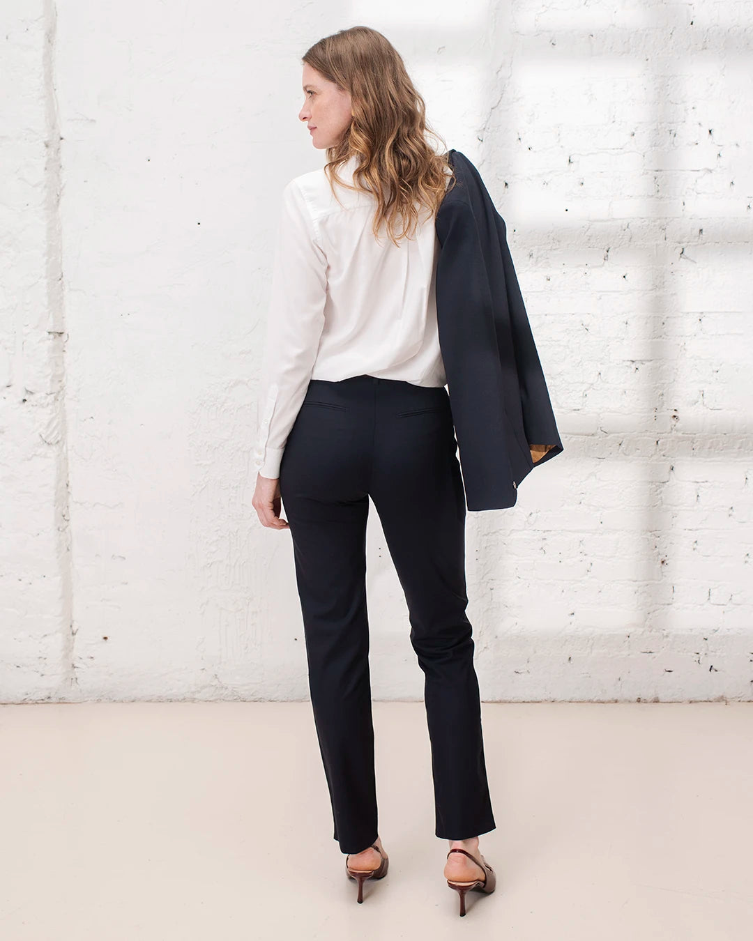 Outfit travail femme avec tailleur bleu marine, veste croisée structurée et pantalon cigarette.